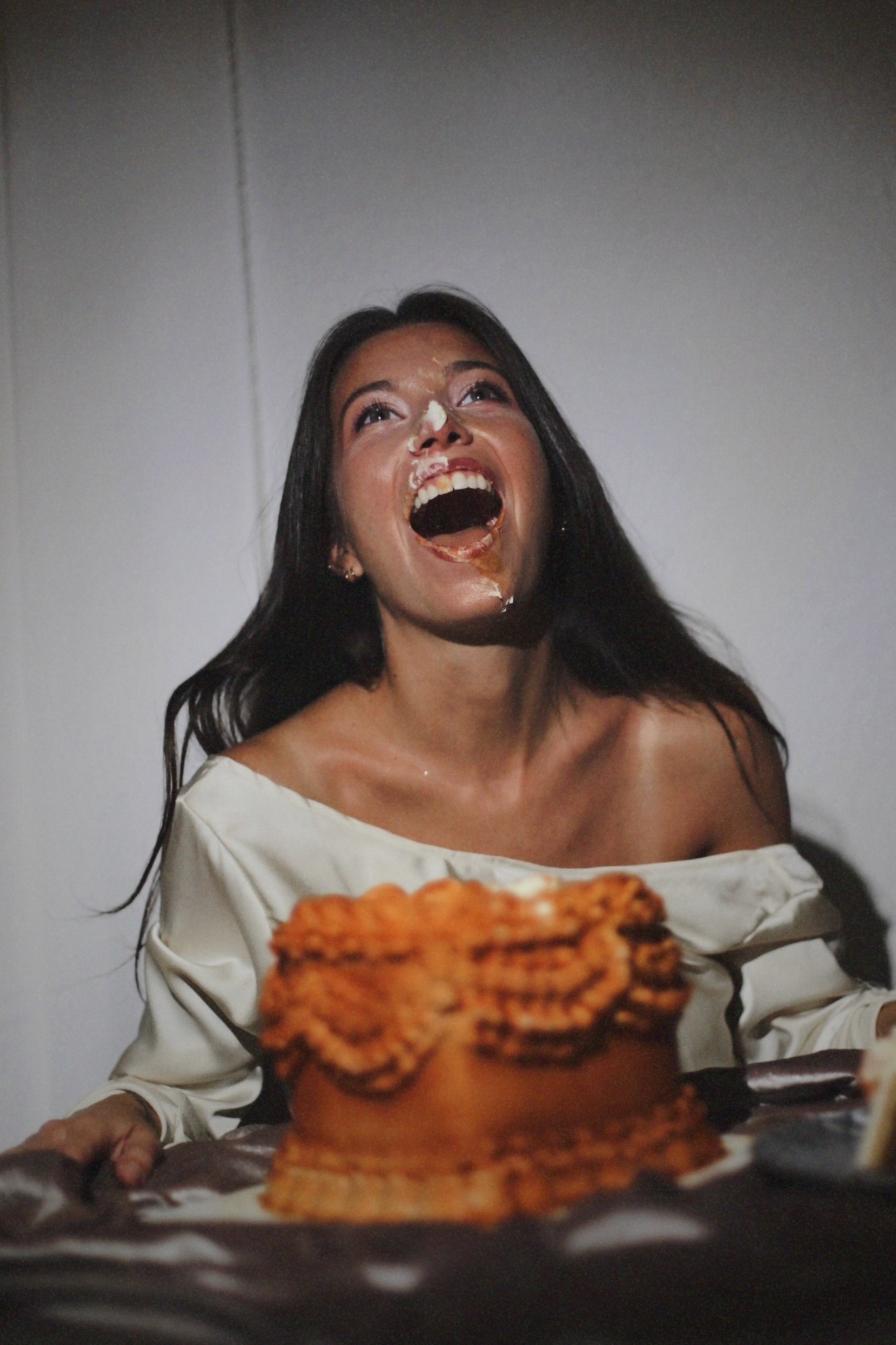 Mujer riendo con crema en la cara junto a una tarta corazón vintage