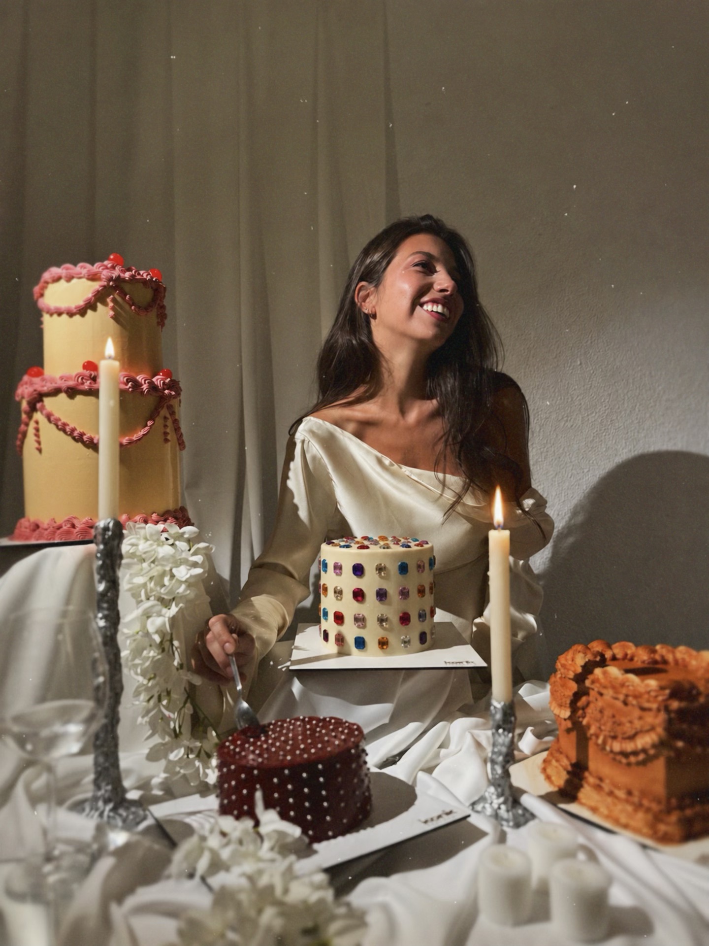 Mujer riendo junto a tartas de dos pisos y velas